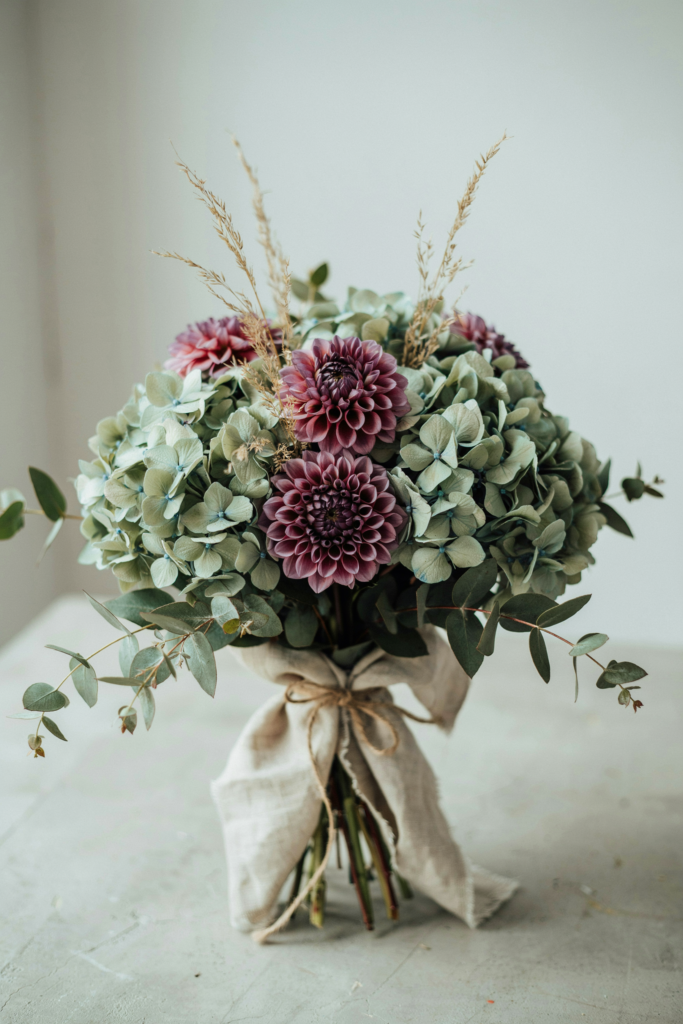 Sophisticated bouquet of soft sage green hydrangea clusters with deep plum dahlias and muted greenery