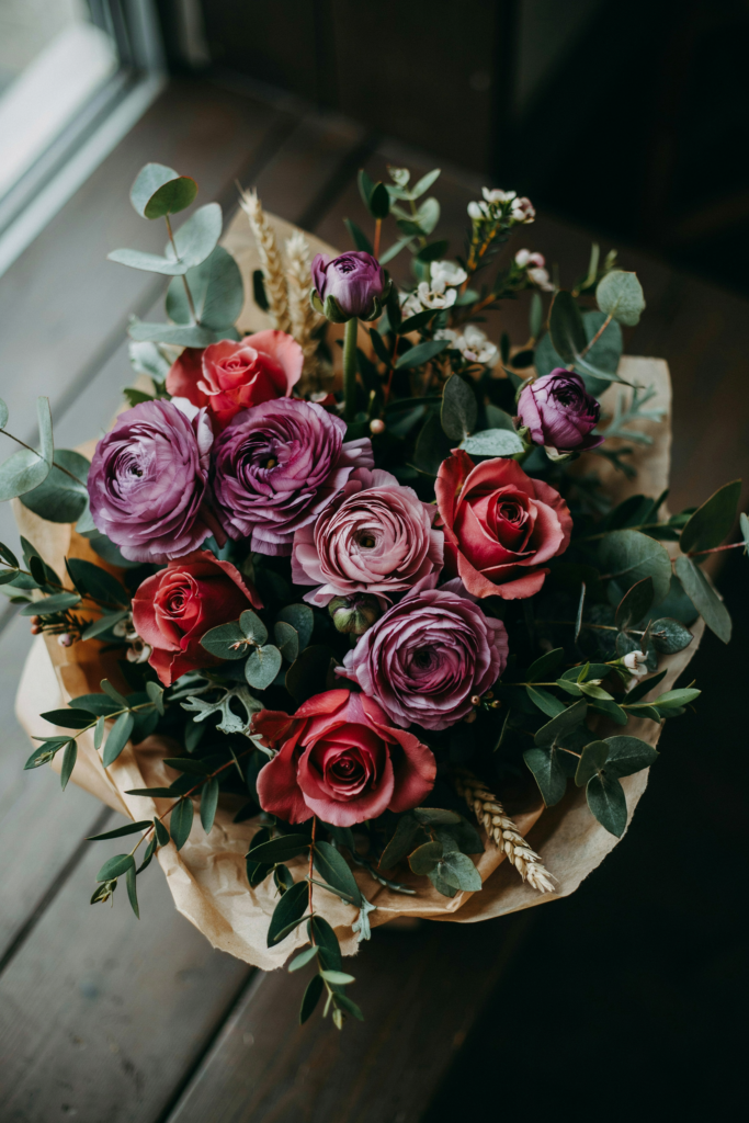 Rich, textural bouquet of deep purple ranunculus layered with burgundy roses and dark greenery