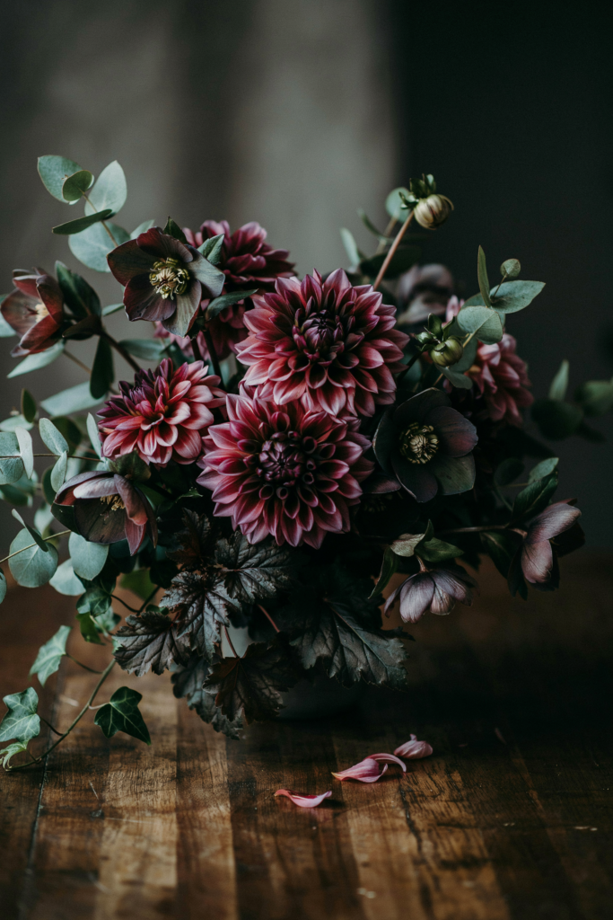 Dark, moody bouquet of eggplant-toned dahlias with nearly-black hellebore flowers and deep greenery