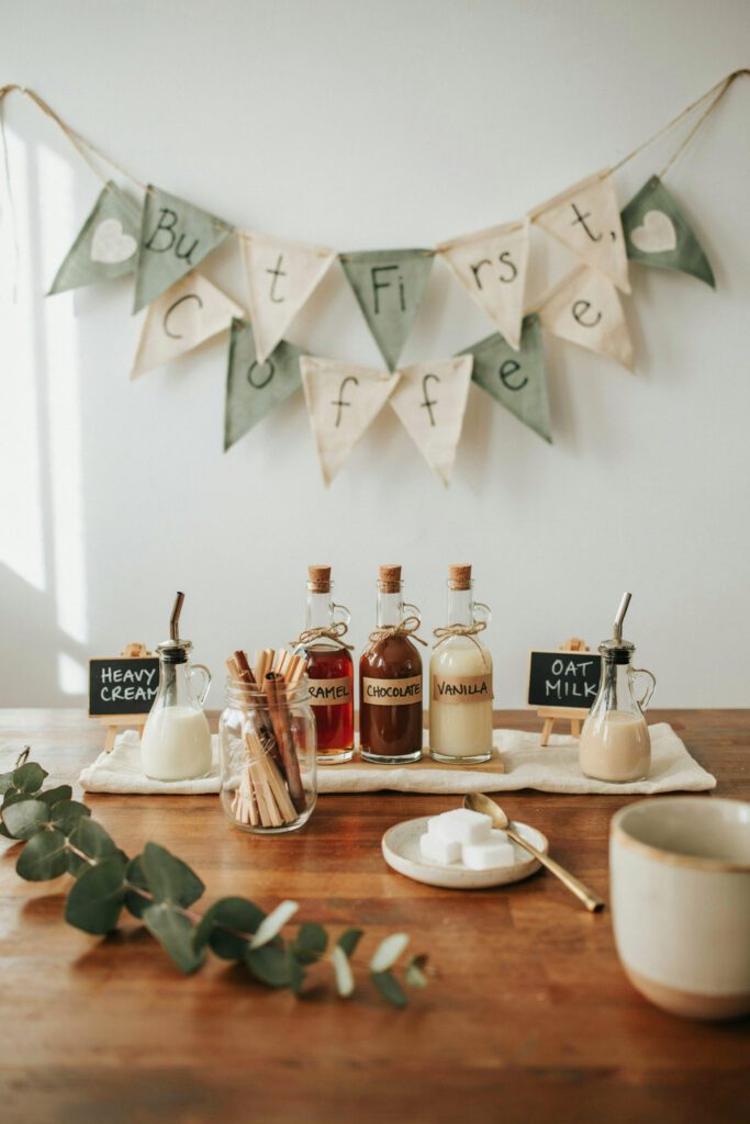A beautifully styled coffee station on a wood-toned table — a complete coffee bar kit with labeled syrups