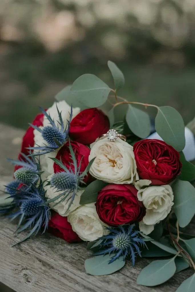 Red and white rose bouquet with blue thistle and eucalyptus