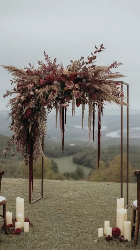 Dried pampas grass and burgundy floral ceremony arch overlooking a hillside view