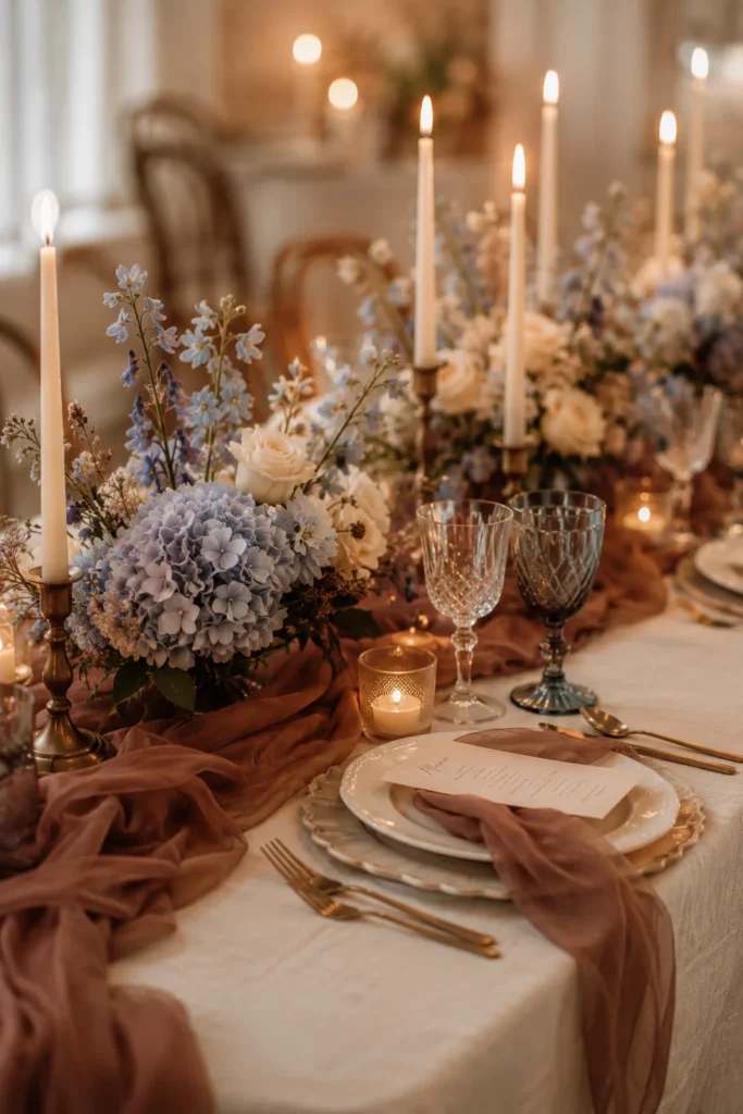 Mocha mousse and icy blue winter wedding tablescape with cream taper candles and soft chiffon draping