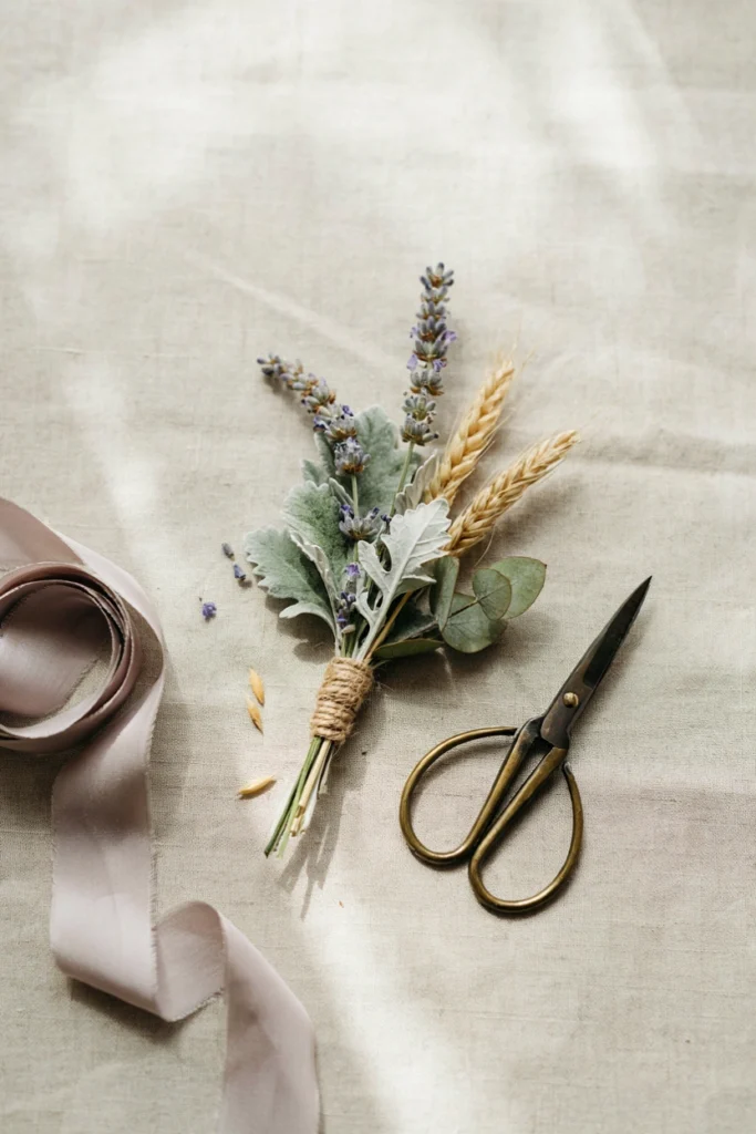 A groom's lavender and dried wheat boutonniere pinned to a linen suit lapel in close-up detail