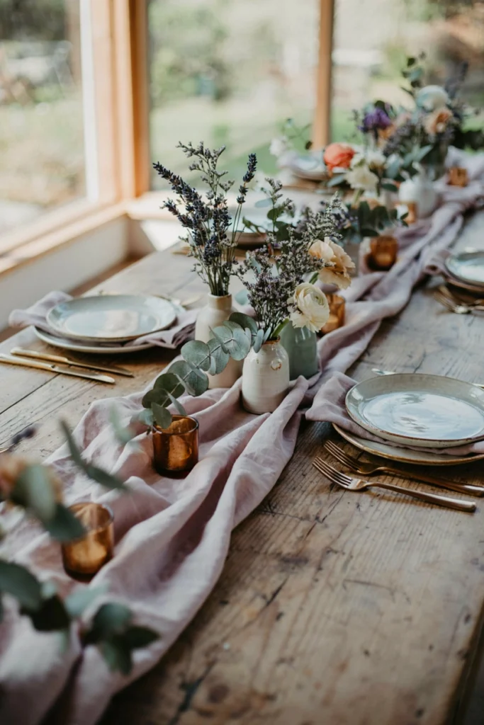 Low textural centerpieces mixing dusty lavender stems with silvery sage and eucalyptus in mismatched ceramic vases