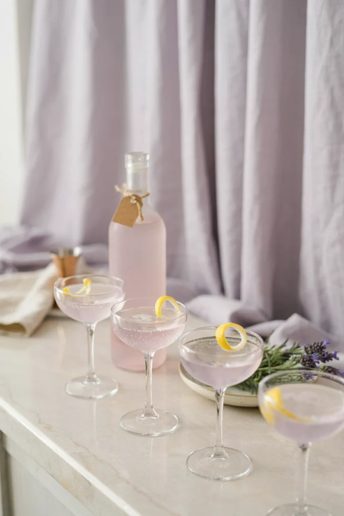 A bar cart styled with lavender simple syrup, fresh lavender garnish, and pale purple cocktails in coupe glasses