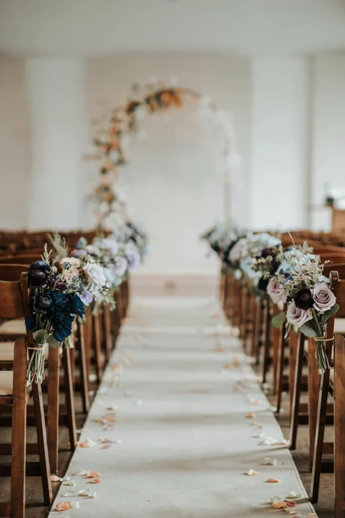 Ombré navy to icy white floral aisle markers on chairs down a winter wedding aisle