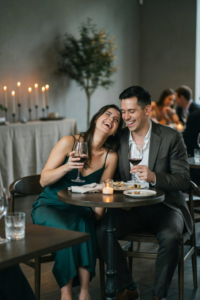 A couple laughing and relaxed at an intimate dinner reception, clearly enjoying the moment rather than being pulled in 10 directions