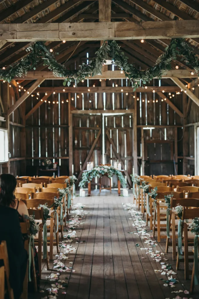 Thick eucalyptus garland strung along the barn's main center beam, hanging in soft swags above the aisle