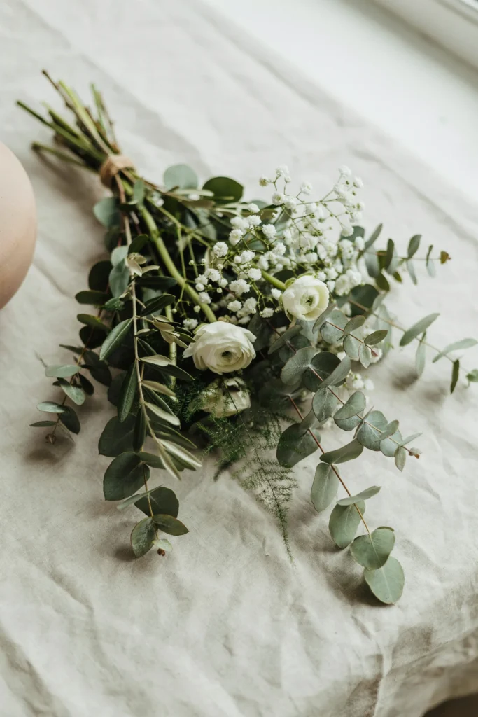 A loose bouquet with long trailing eucalyptus stems woven through baby's breath, greenery-forward and organic.