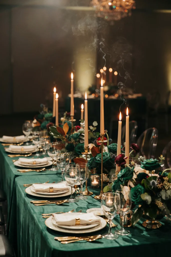 Emerald green velvet linens paired with gold candlesticks and deep green florals on a formal reception table