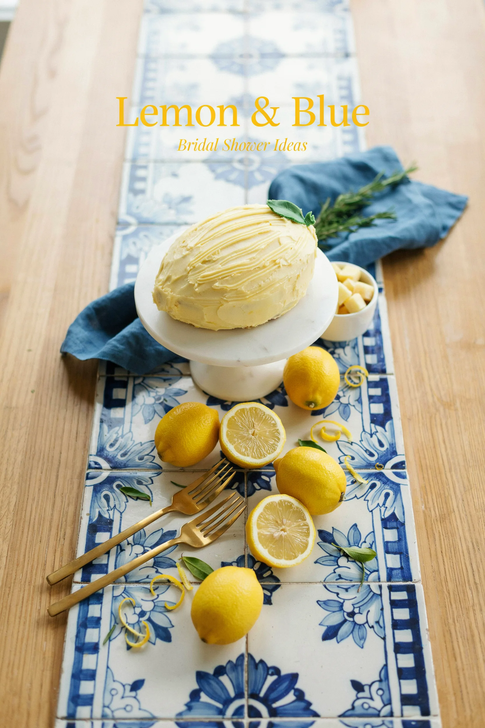 Overhead shot of a blue-and-white tiled table runner topped with fresh lemons, blue linen napkins, and a lemon-shaped cake, with soft natural light and a "Lemon & Blue Bridal Shower Ideas" text overlay in a citrus-yellow serif font.
