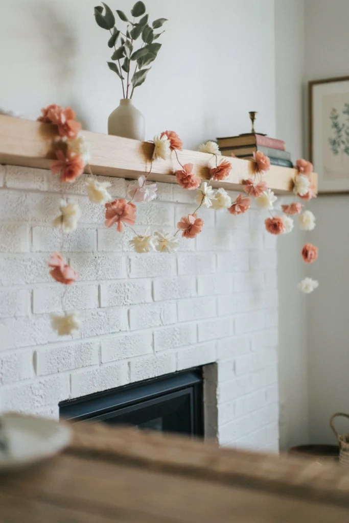 Handmade tissue paper flower garland in blush and cream strung along a mantel