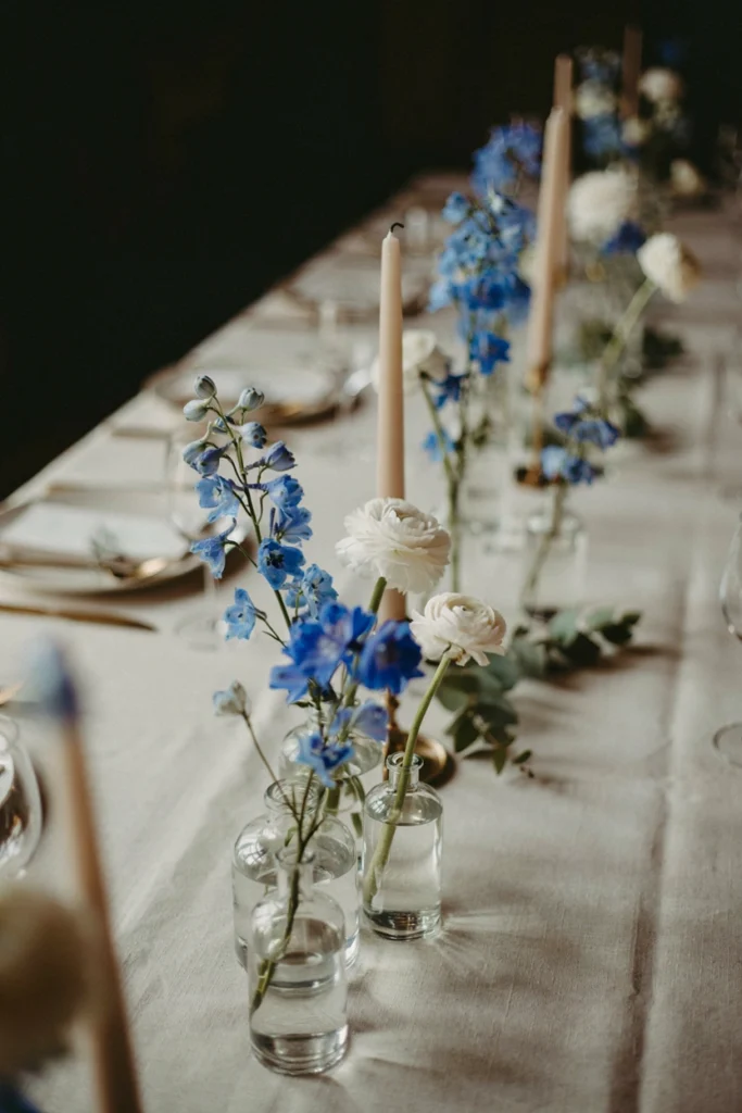 French blue delphinium bud vase clusters lining a wedding reception table