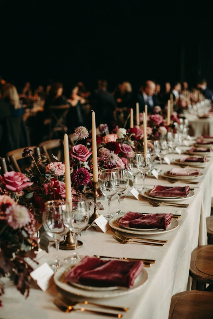 Minimalist reception table with a single raspberry rose accent among white blooms and trailing greenery