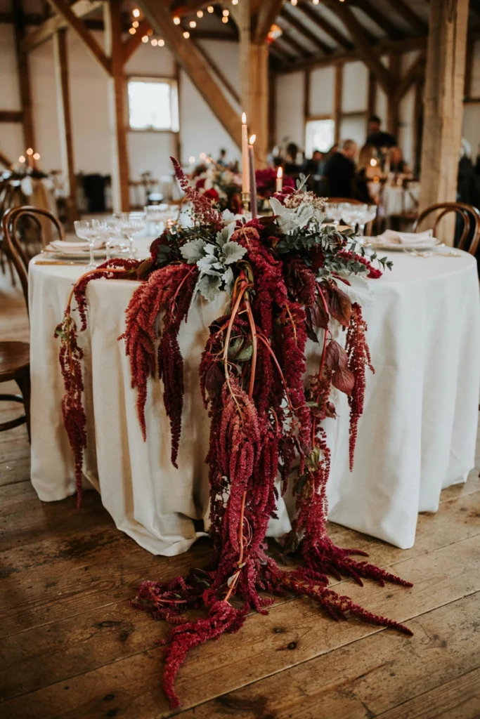 Deep burgundy trailing amaranthus garland cascading over the edge of a wedding sweetheart table