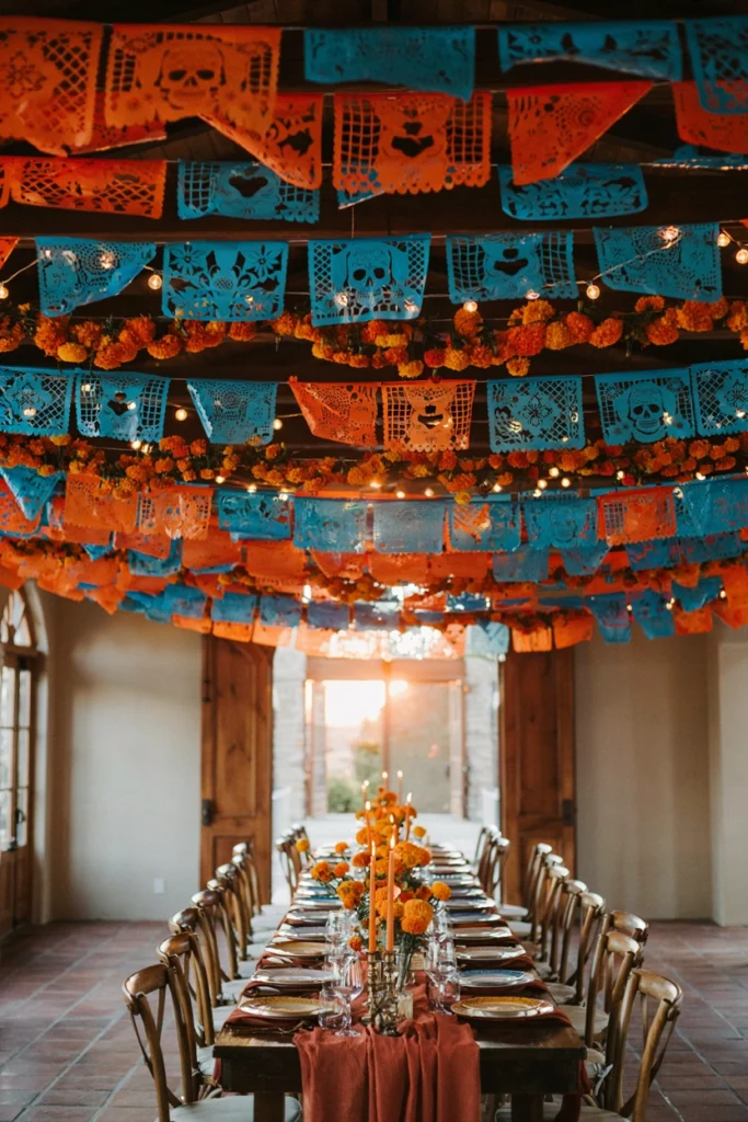 Wedding reception strung with cobalt and marigold papel picado banners alternating with fresh marigold garlands