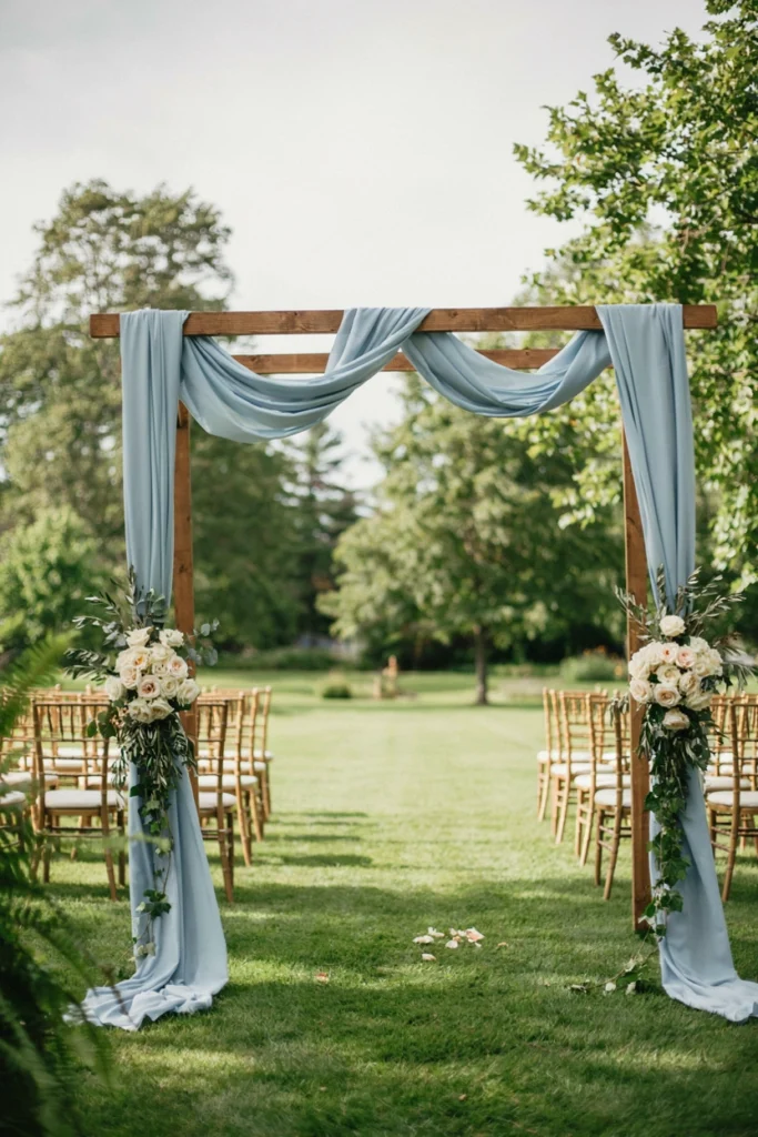 French blue ribbon-draped wedding ceremony arch with ivory roses and gold chairs