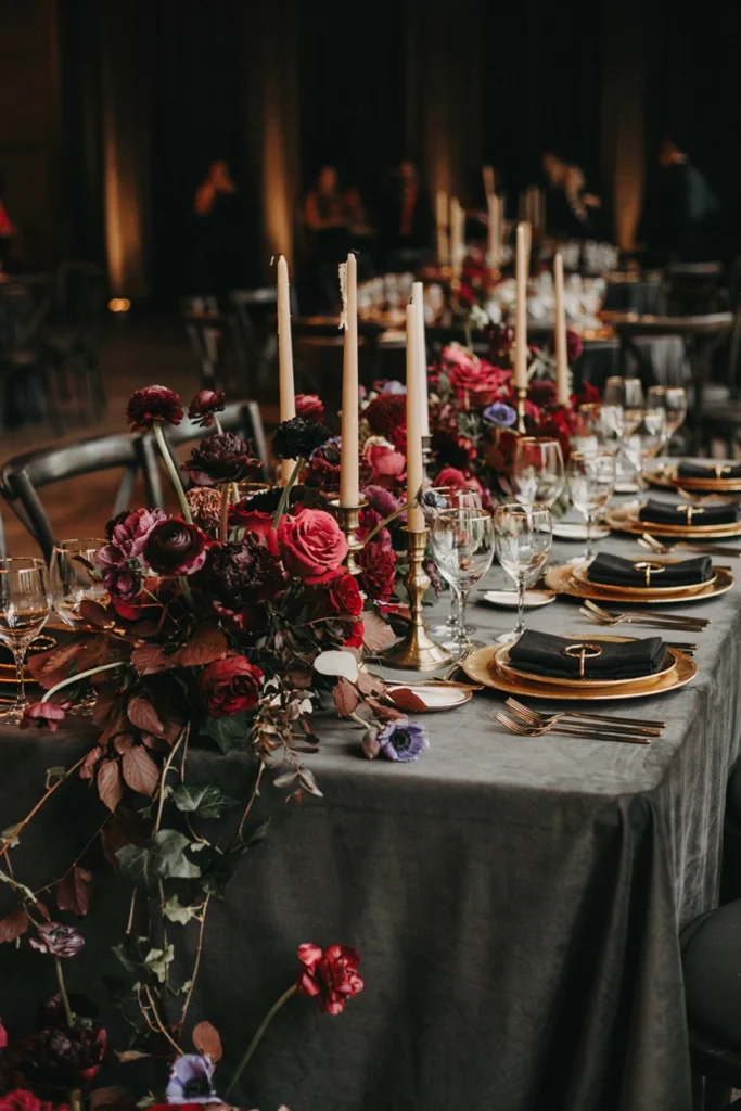 Moody reception table in charcoal linens with raspberry florals and silver taper candlesticks