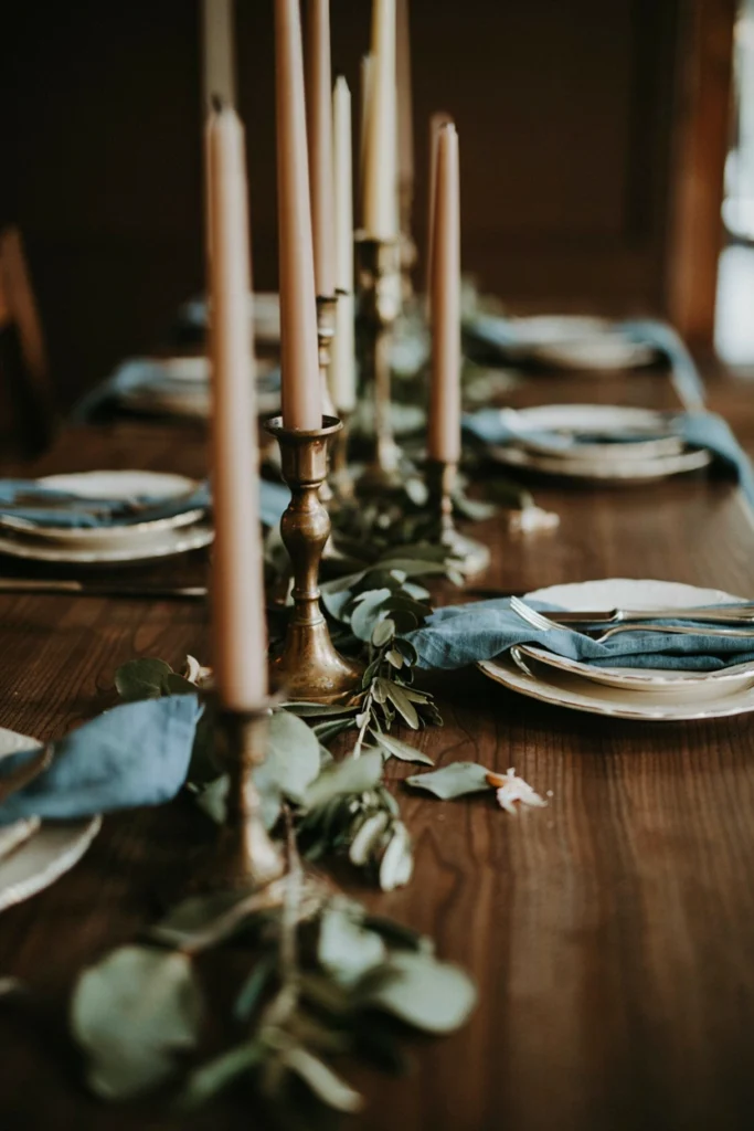 Brass candlesticks and French blue linen napkins on a moody wedding tablescape