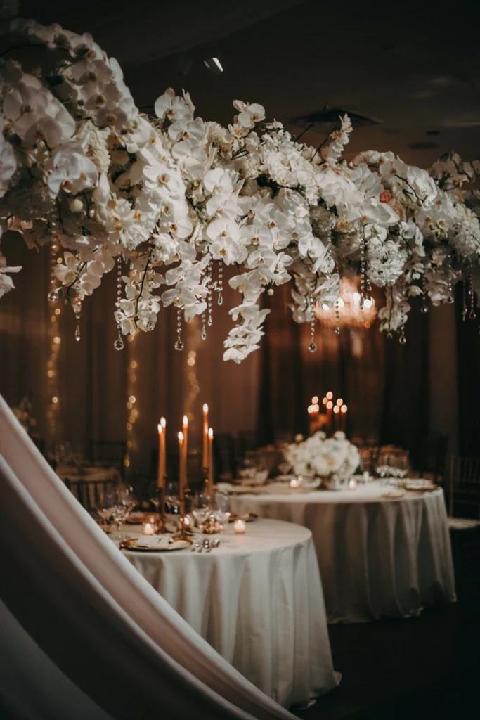 Hanging garland of white cascading orchids interspersed with crystal strands suspended above a wedding table