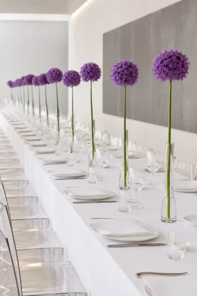 Single purple allium stem centerpiece in a slim glass vase