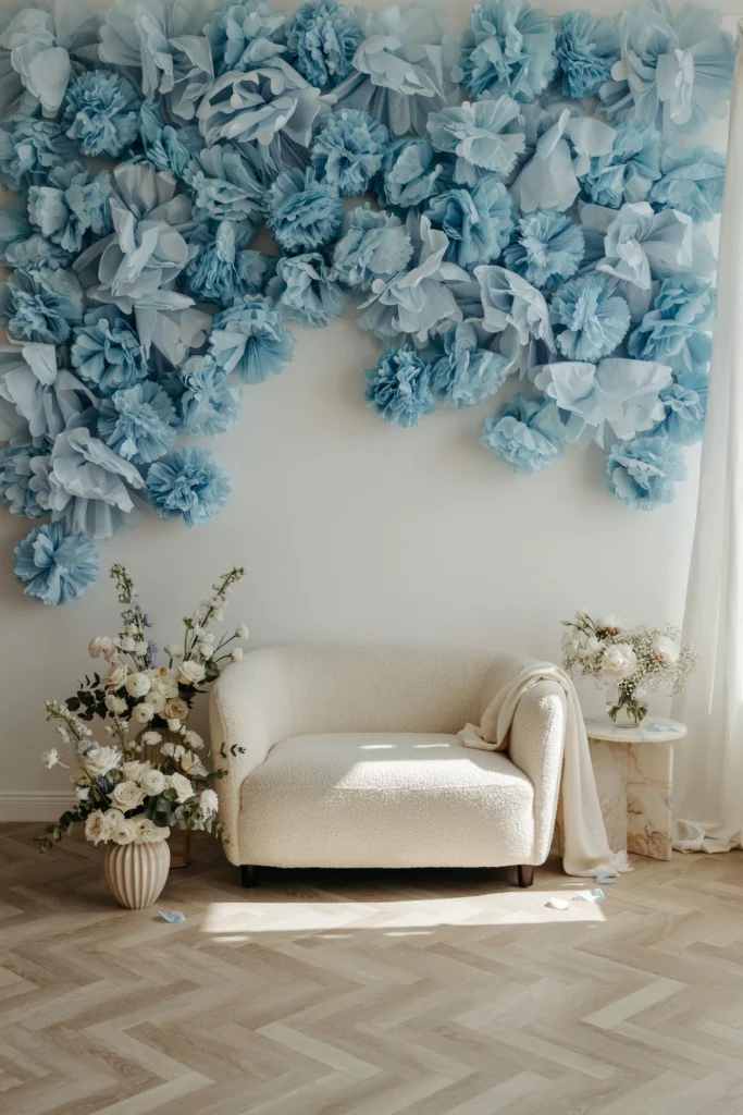 Wall of dusty blue tissue paper pom poms clustered into a bridal shower photo backdrop