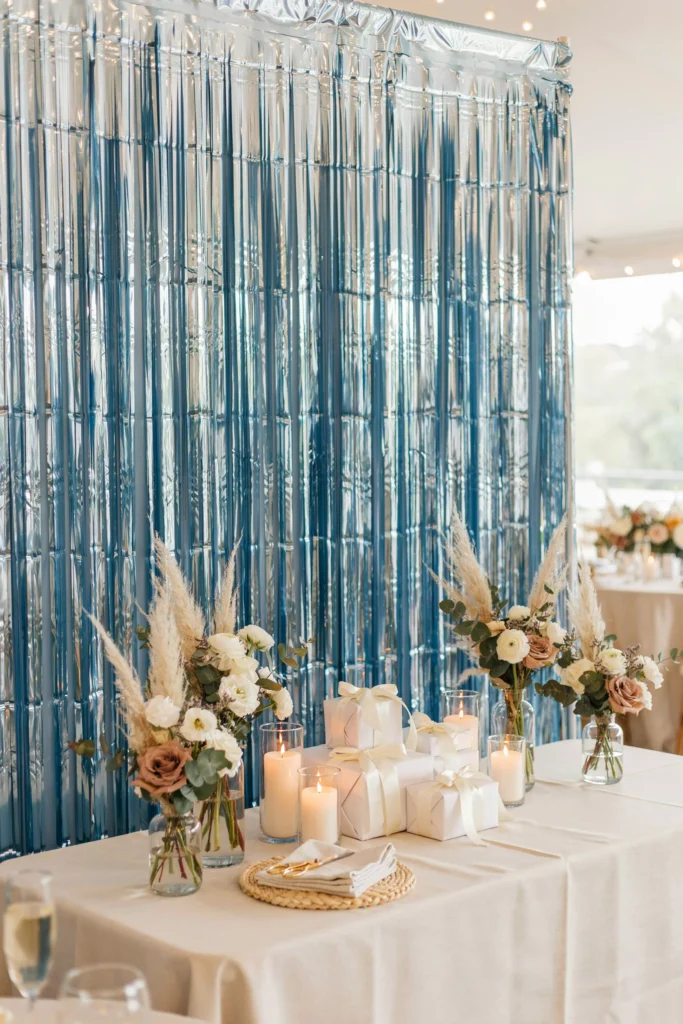 Shimmering blue fringe curtain backdrop behind a coastal-themed bridal shower gift table
