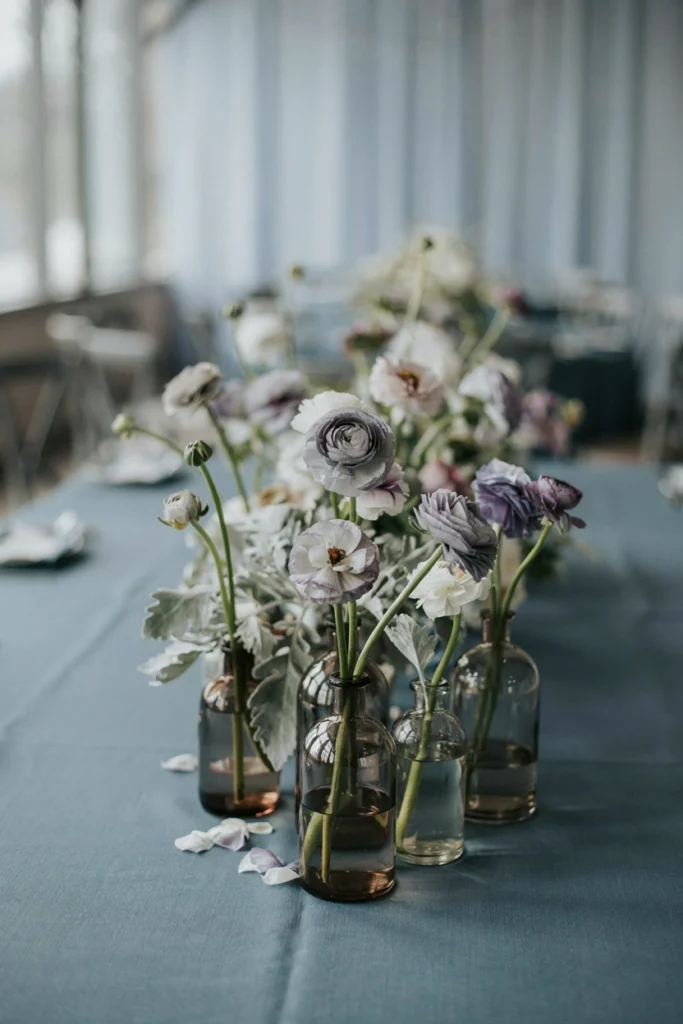 Slate blue winter wedding table with smoked glass bud vases and dusty miller
