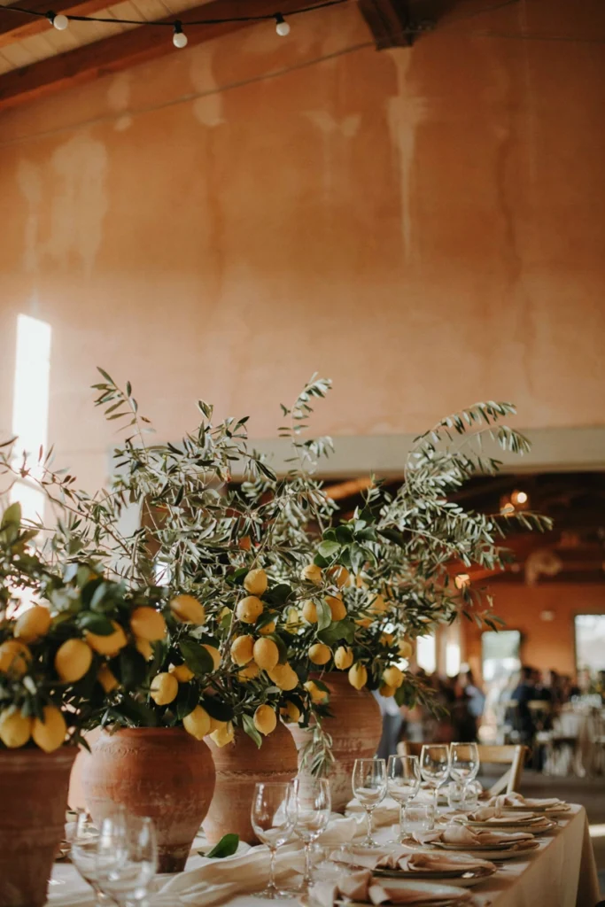 Terracotta pots with lemon branches styled against an ochre wall for a Mediterranean wedding photobooth
