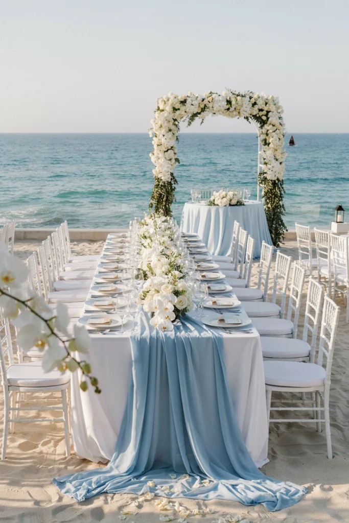 Sea-glass blue linen runner over white tablecloths with white florals