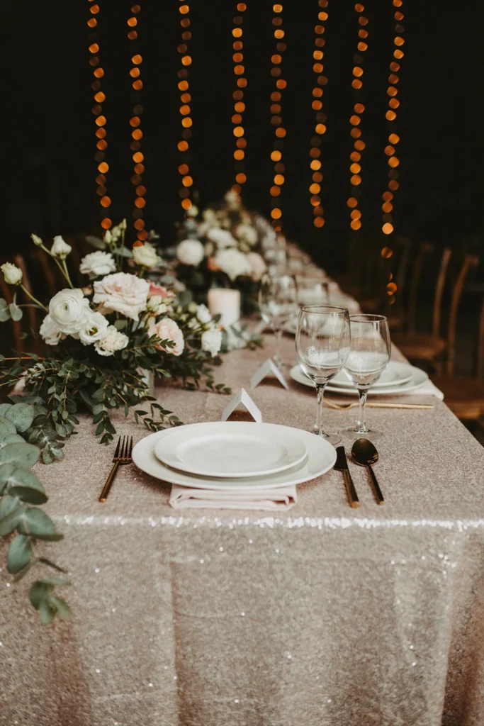 Shimmering blush sequin tablecloth set with taper candles and low white florals