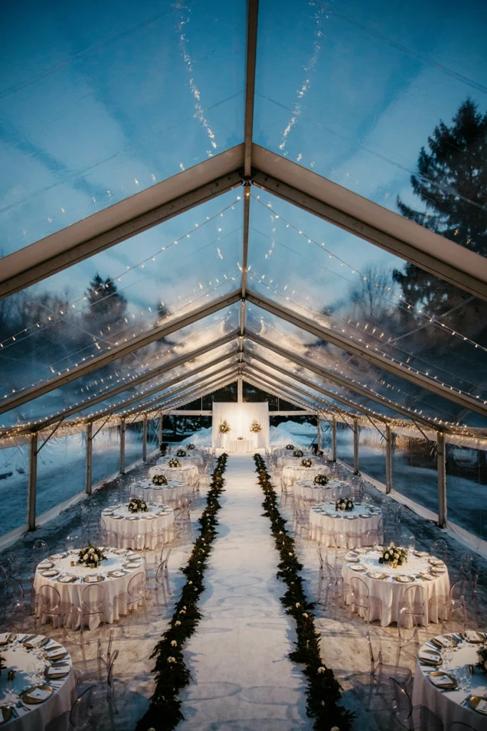 Outdoor tented winter wedding reception for 200 guests with string lights and long banquet tables