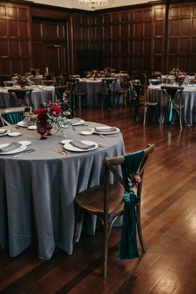 Dark wooden wedding chair tied with an emerald velvet sash and a single eucalyptus sprig