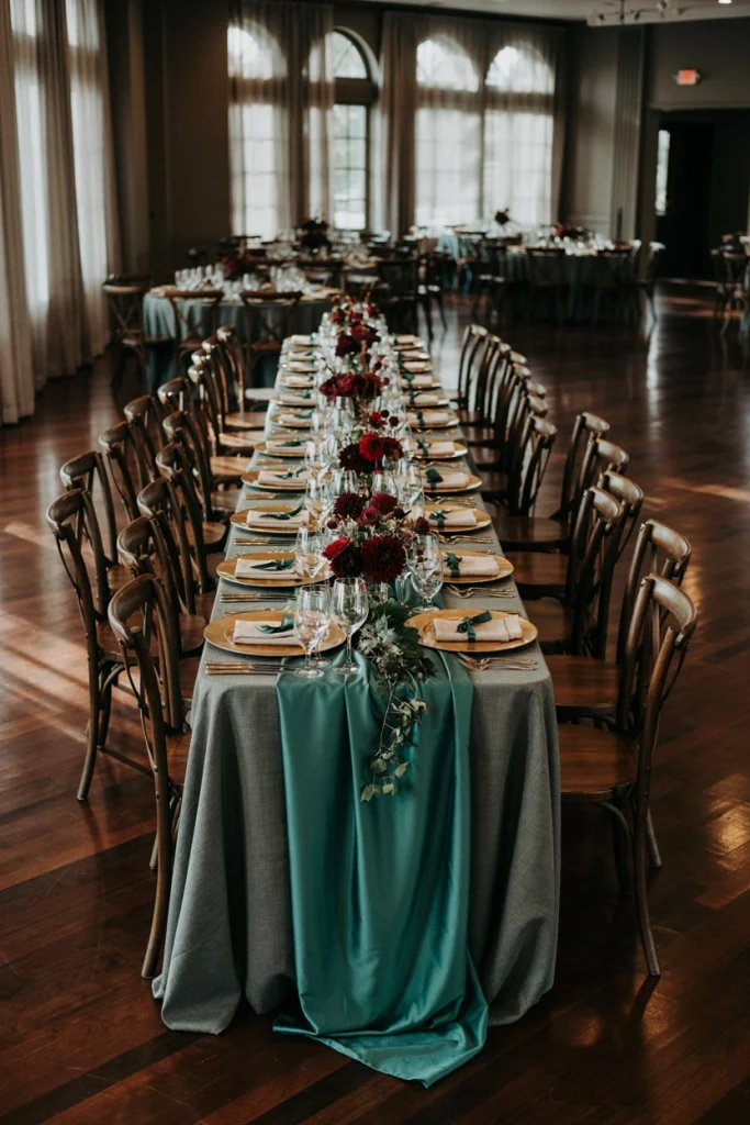 Row of dark stained wooden cross-back chairs left bare against deep colored wedding linens