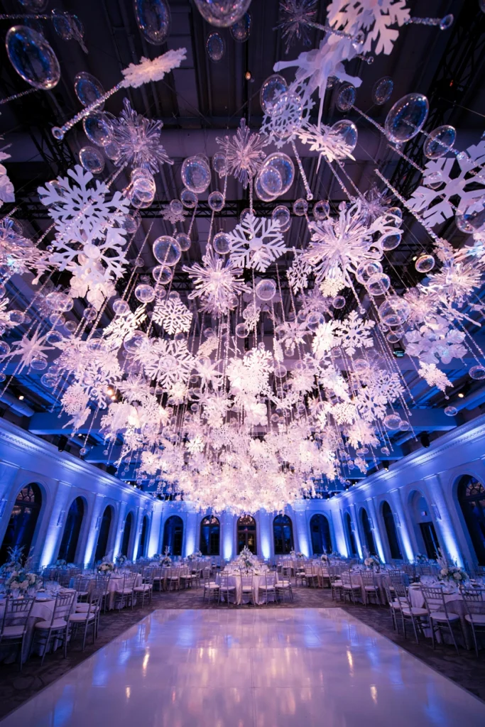 Reception ceiling with dozens of iridescent snowflake cutouts suspended above the dance floor