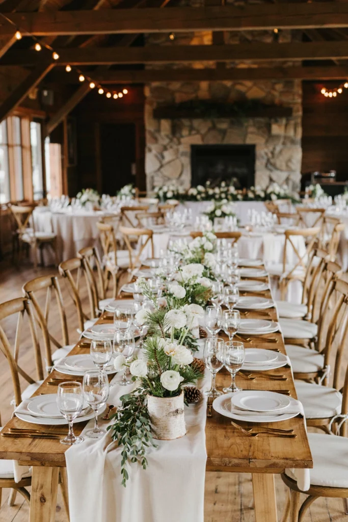 Hollowed birch log candle holders clustered on a wedding table with white ranunculus