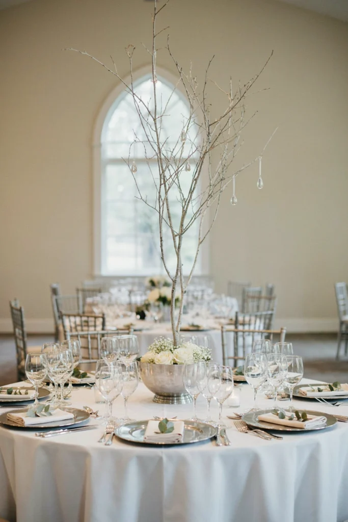 Tall white branch centerpiece with hanging crystal drops in a silver vase
