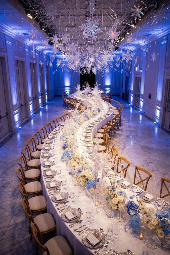 Overhead view of one long curving banquet table indoors dressed in white and silver with crystal garland
